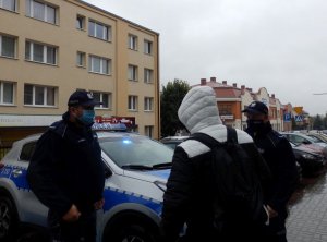 Policjanci legitymujący osobę, która nie przestrzegała obostrzeń sanitarnych